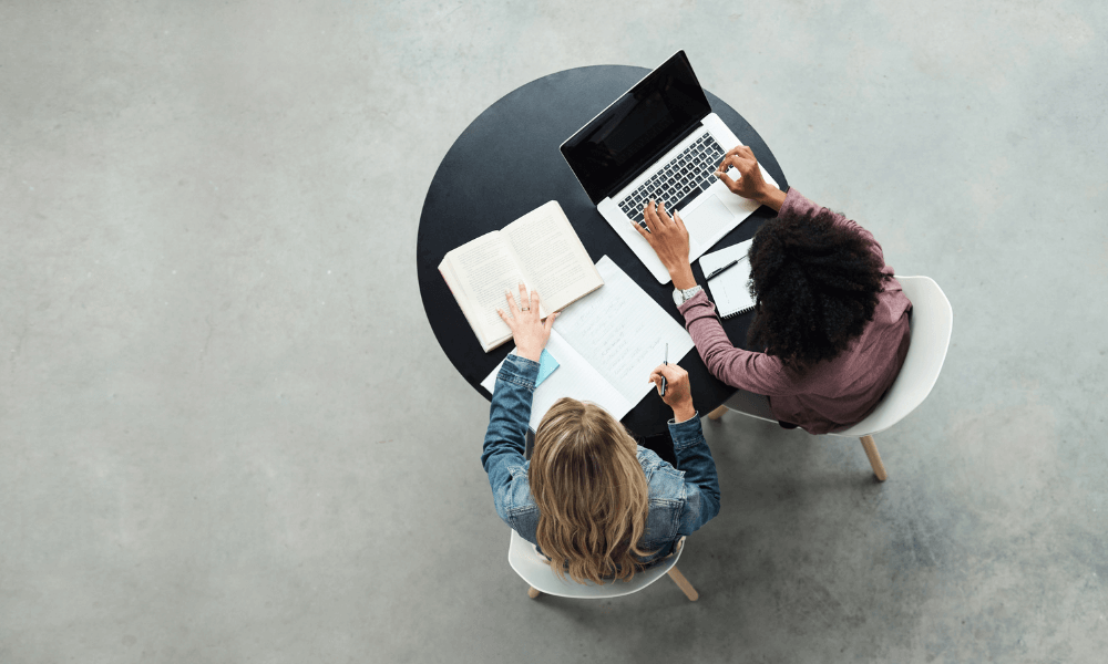 Hvem er et kursus i distanceledelse relevant for? - to personer sidder ved bord med computer