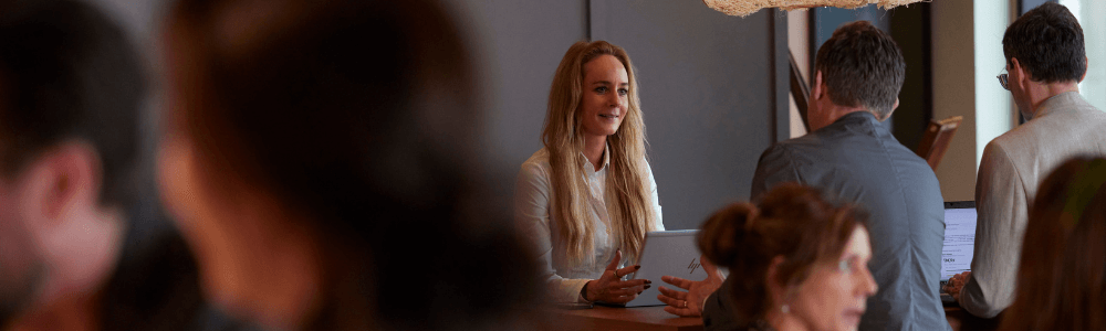 Kvinde ved computer sidder overfor mand og taler