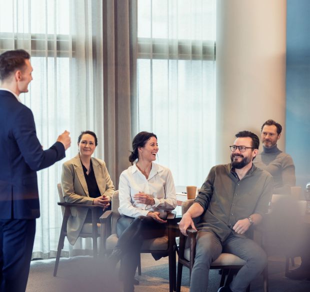 Mand taler foran gruppe af glade mennesker Mand taler foran gruppe af glade mennesker