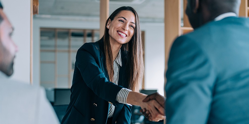 Professionel medarbejder byder kunde velkommen med et håndtryk og signalerer god service og personlig dialog.