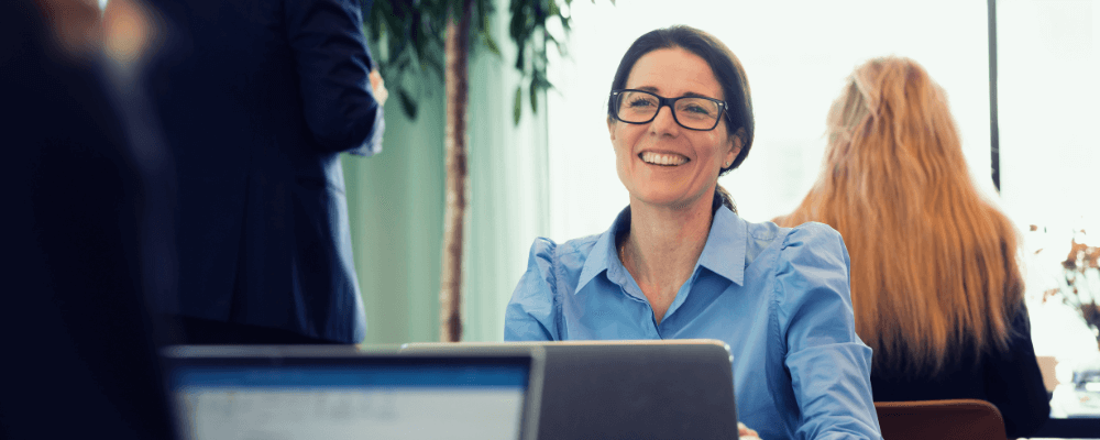 Motivational Leadership: smilende kvinder der sidder ved sin computer